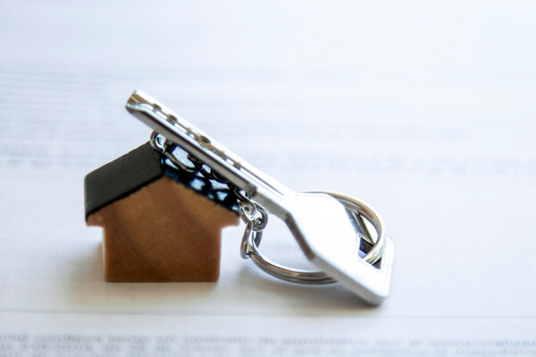 ein Schlüsselanhänger in Form eines Hauses mit Schlüssel daran | © Adobe Stock