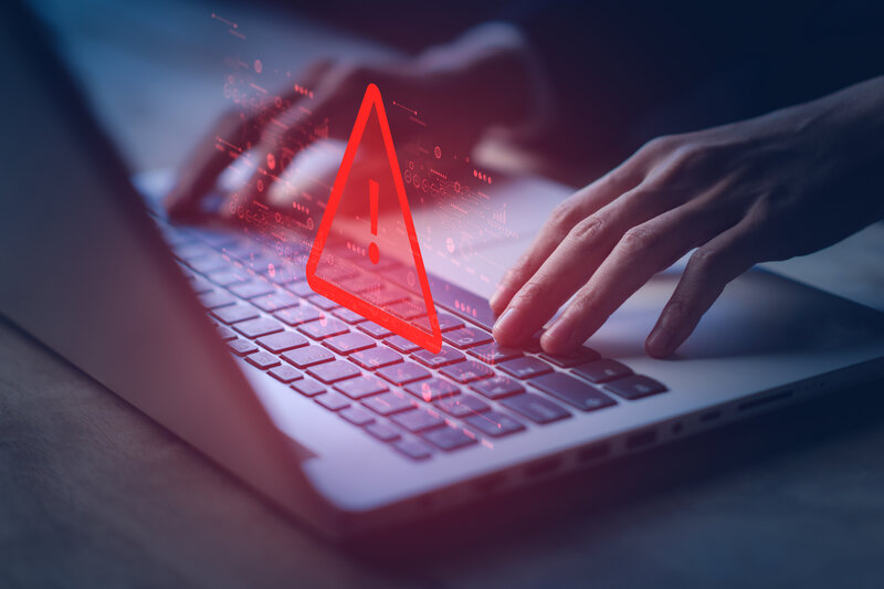 Ein leuchtendes Warnsymbol über einem aufgeklappten Laptop | © Adobe Stock